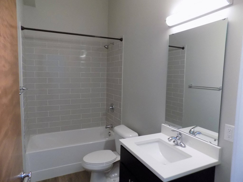 A white sink is on a countertop next to a white toilet in a bathroom.