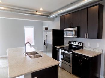 A kitchen with black cabinets and stainless steel appliances.
