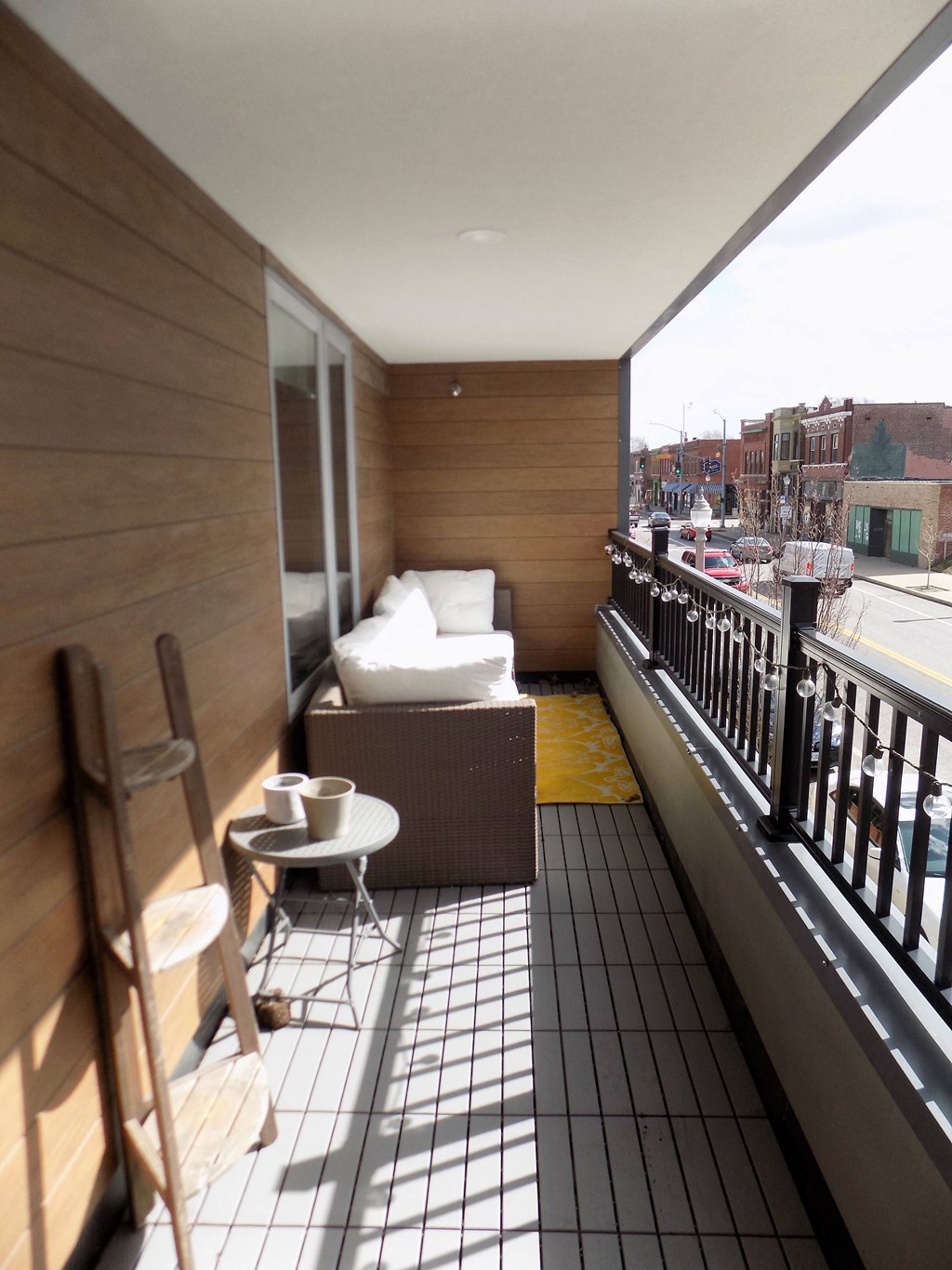 A balcony with a chair, table, and a bag of chips.