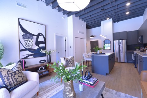 A living room with a white couch and a coffee table with a vase of flowers on it.