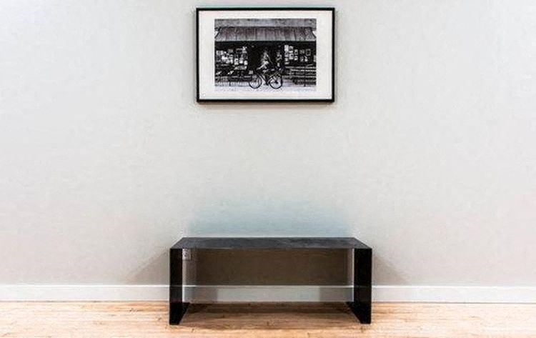 A black and white picture of a bicycle is hanging on a wall above a black coffee table.