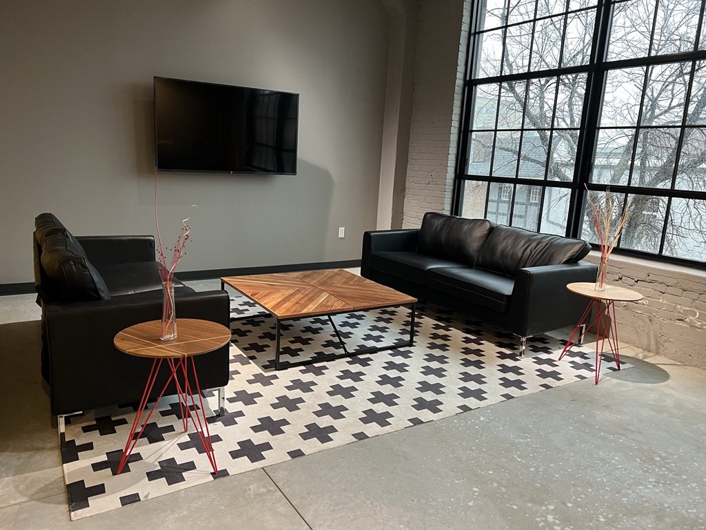 a living room with black leather couches and a black and white checkered rug