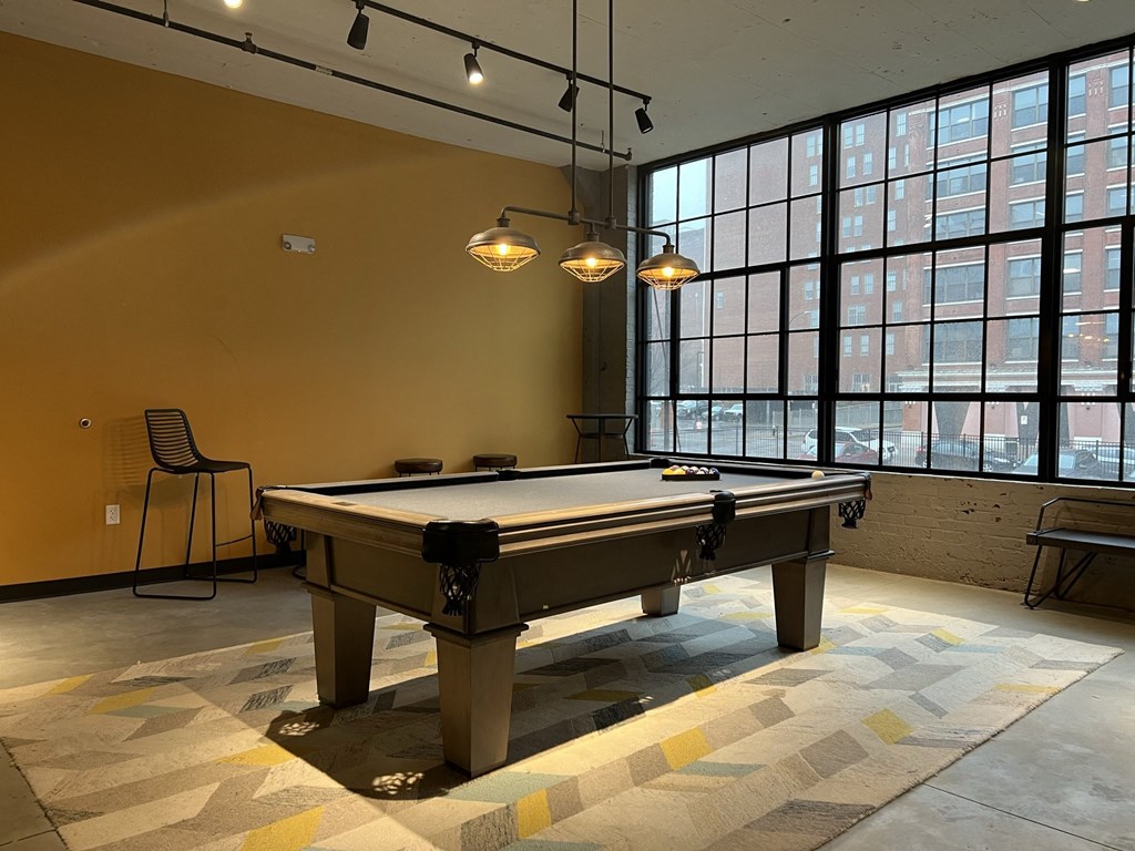 a pool table sits in the middle of a room with large windows and a yellow wall