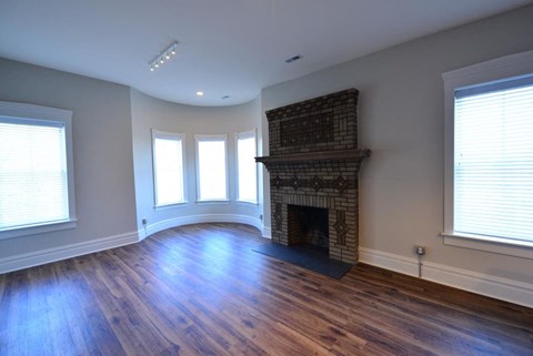a living room with a brick fireplace and wooden floors