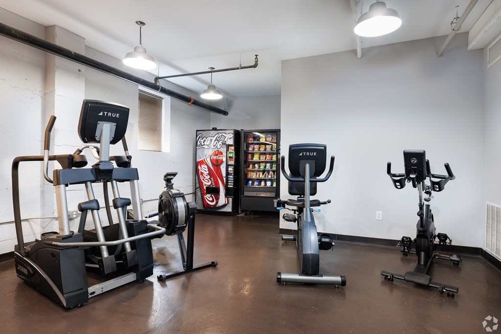 A gym with a variety of equipment including a rowing machine, a stationary bike, and a treadmill.