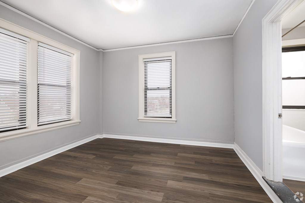 A room with wooden flooring and a window with blinds.