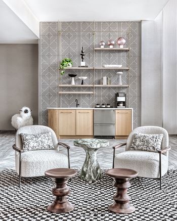 A living room with a patterned carpet and a glass table.