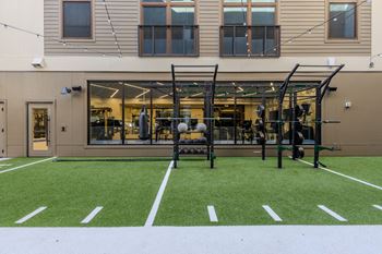 A gym with a green artificial turf in front of a building.