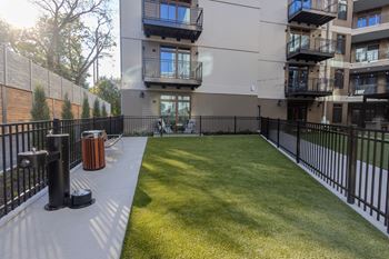 A black fence surrounds a green lawn in front of a building.