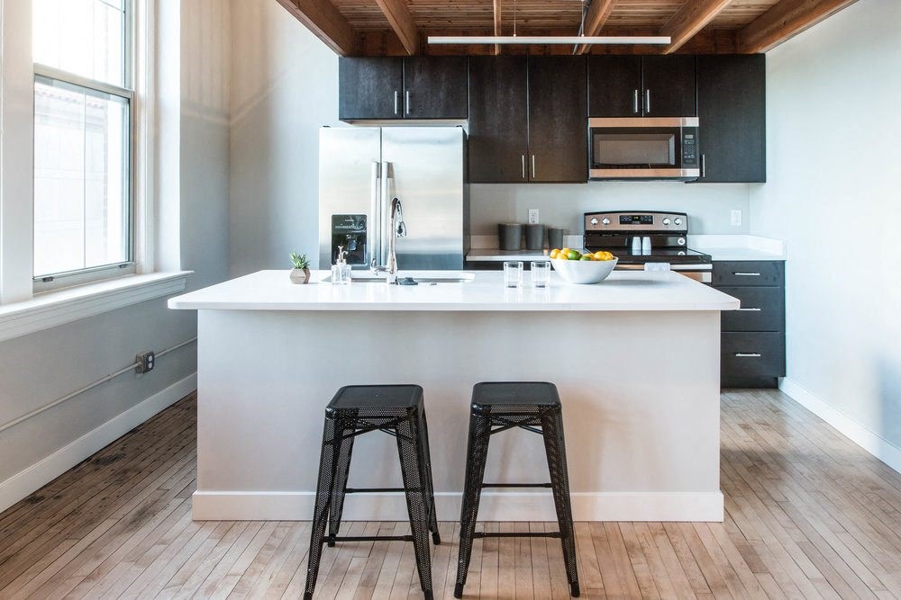 A kitchen with a white island and black stools.