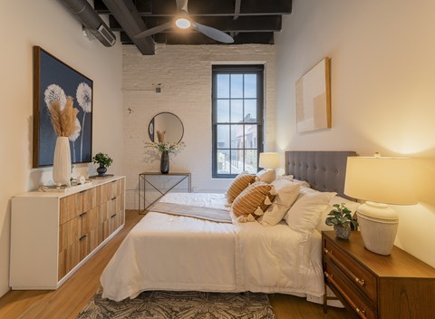 A bedroom with a large bed, a wooden dresser, and a painting on the wall.