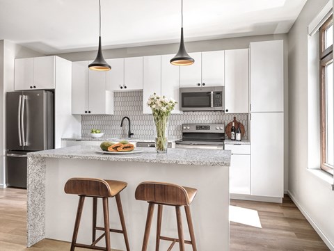 a kitchen with white cabinets and a counter top with two wooden stools