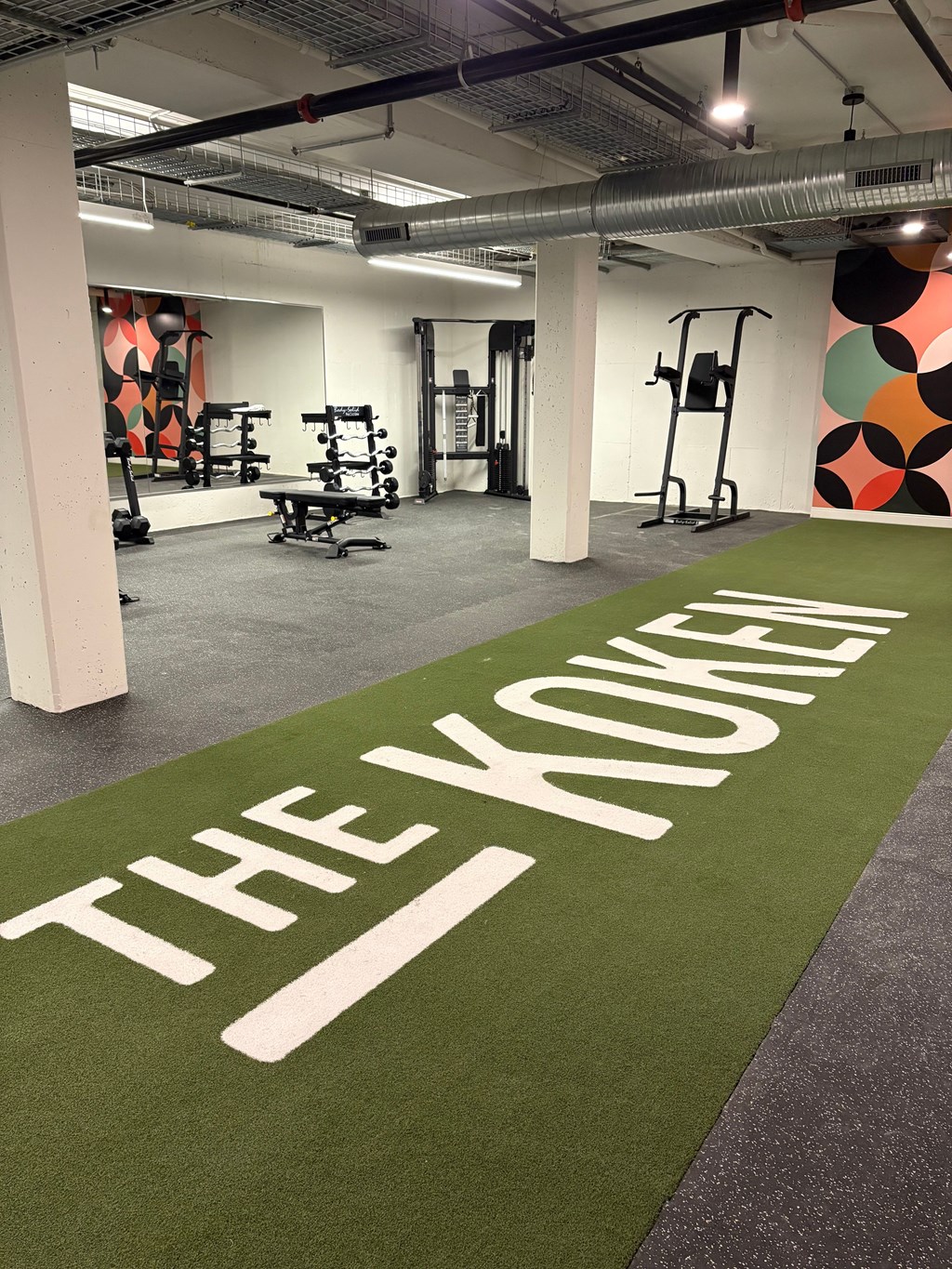A gym with a green carpet that says "The Koukles".