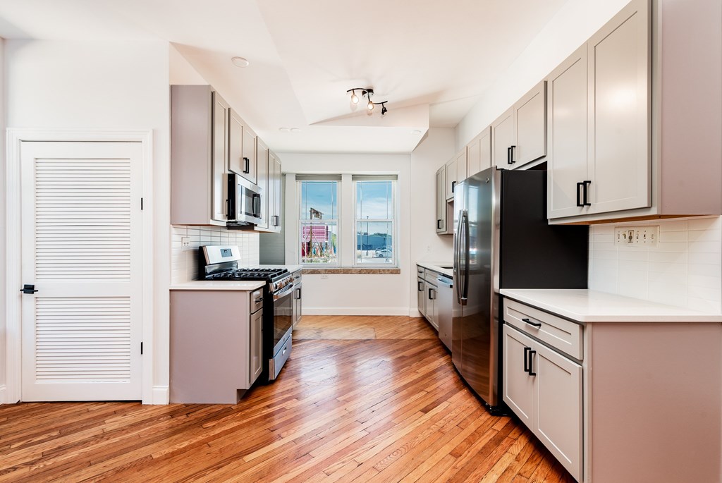 A kitchen with wooden floors and white cabinets.
