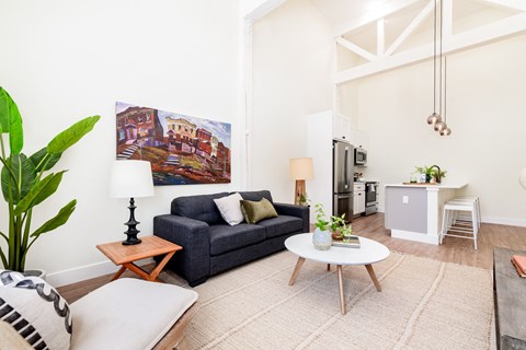 A living room with a blue couch and a painting on the wall.