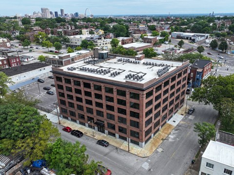 an aerial view of a brick building with a white roof