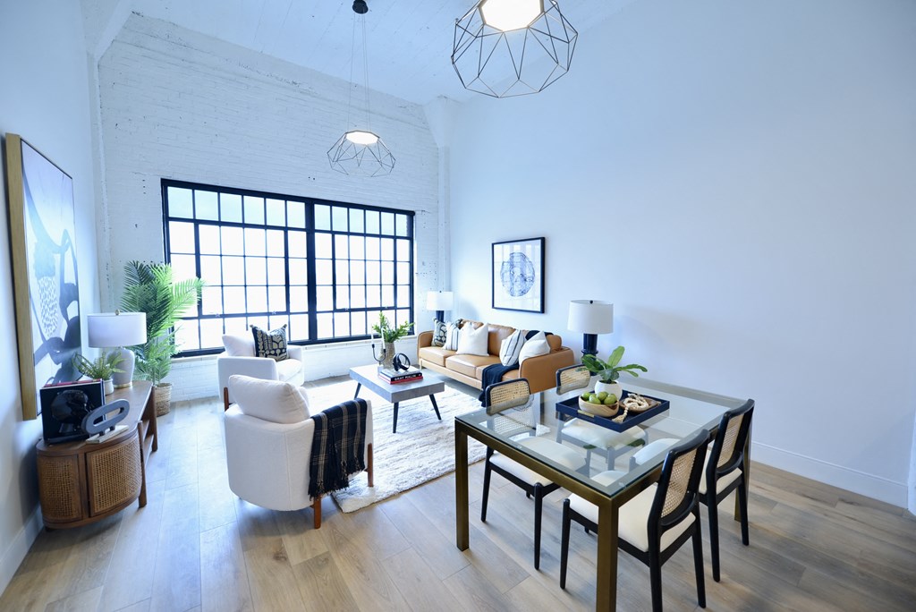 a living room and dining room with white walls and wooden floors