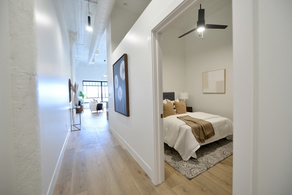 a bedroom with a bed and a hallway to a living room