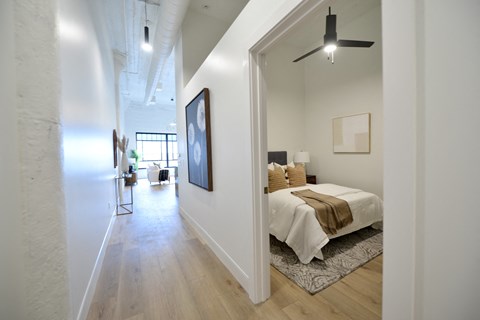 a bedroom with a bed and a hallway to a living room