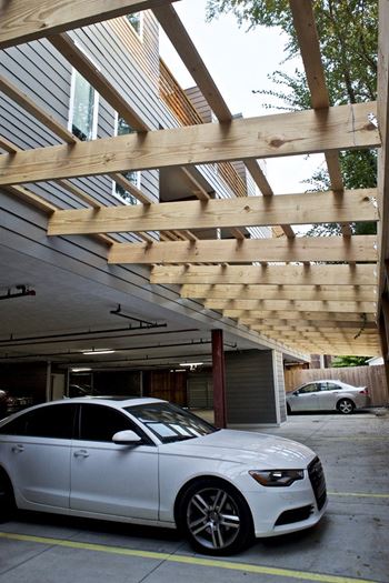 A white car is parked under a wooden structure.