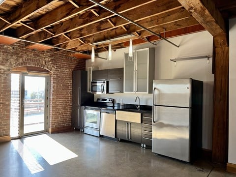 a kitchen with stainless steel appliances and a brick wall