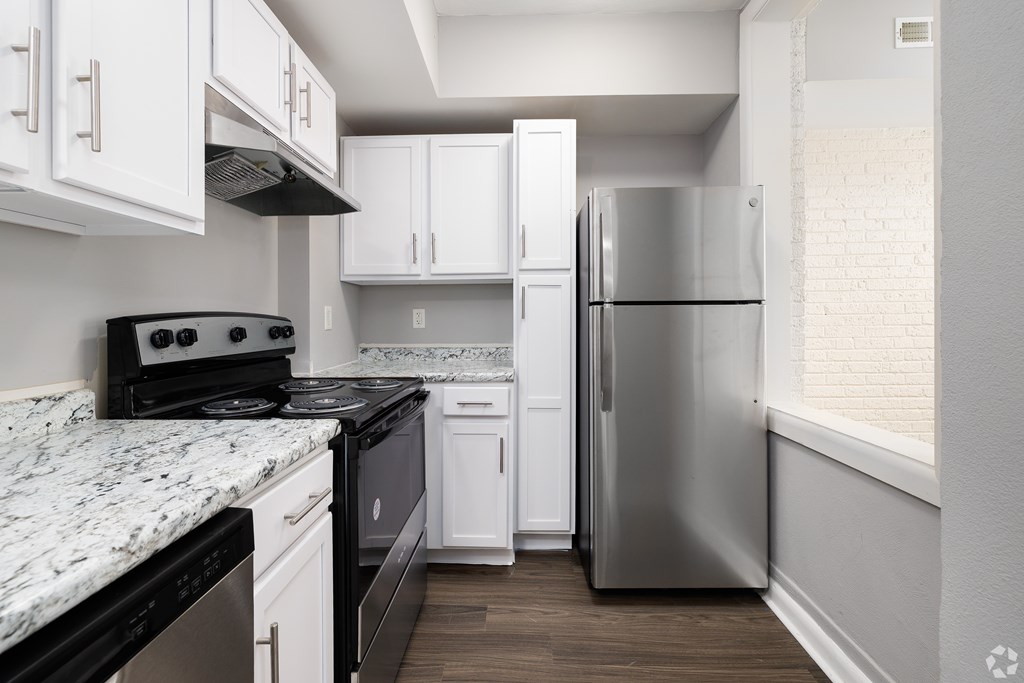 A kitchen with white cabinets and a stainless steel refrigerator.