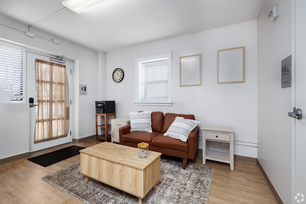 A living room with a brown couch, a wooden coffee table, and a small white table.
