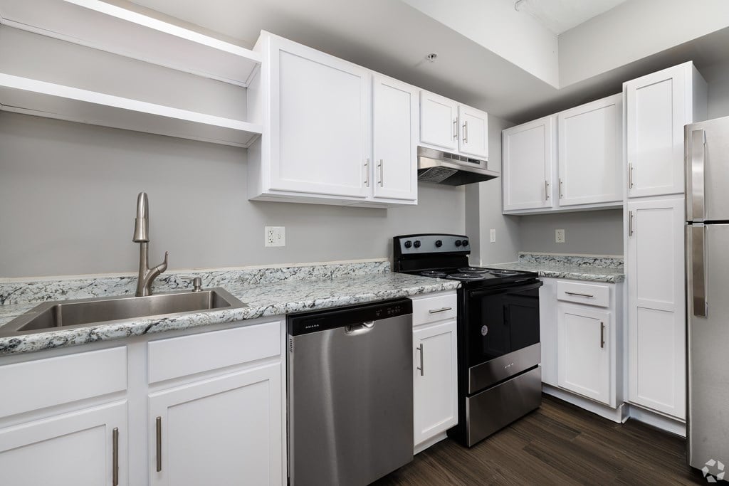 A kitchen with white cabinets and a granite countertop.