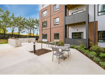 a patio with a table and chairs and a fire hydrant in front of a brick building