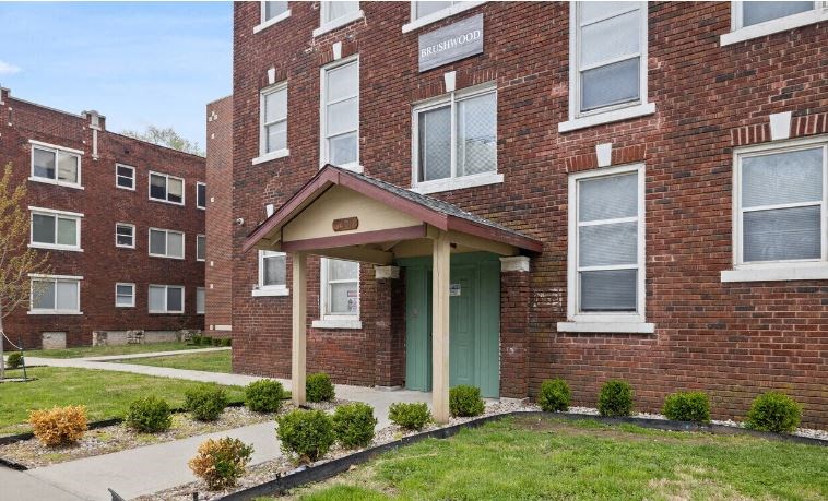 the front of a brick apartment building with a green door