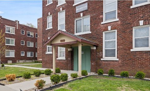 the front of a brick apartment building with a green door