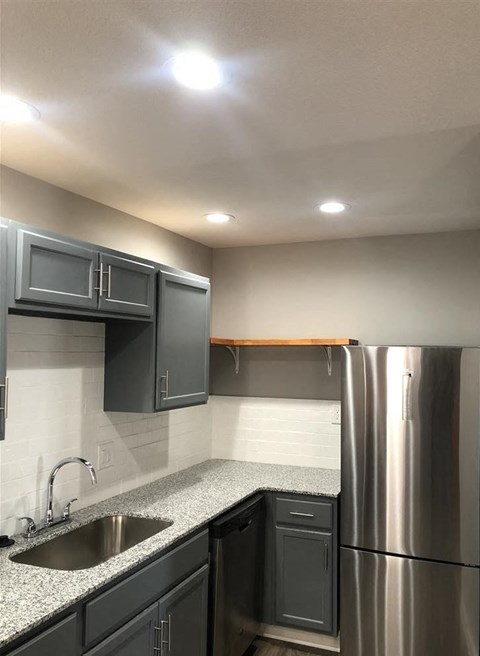 A kitchen with a stainless steel refrigerator and black cabinets.