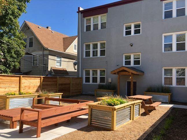 A grey building with a wooden bench in front of it.