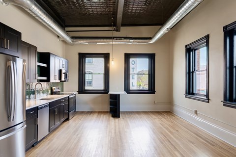 A kitchen with wooden floors and black cabinets.