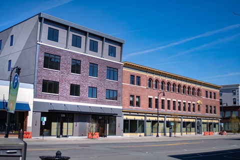 A street view of a city with buildings and a clear blue sky.