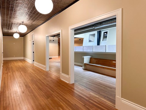 A hallway with wood floors and a bench.
