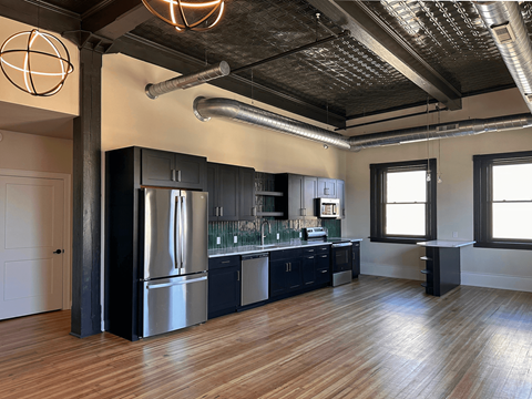 A modern kitchen with a wooden floor and stainless steel appliances.