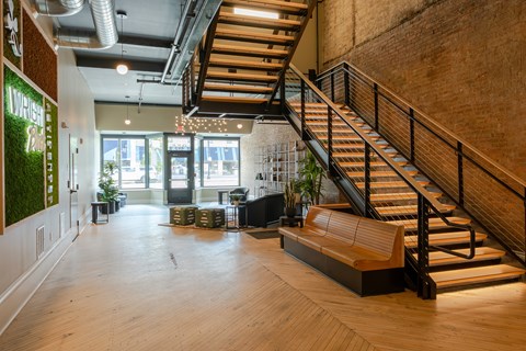 A staircase with a wooden handrail and a bench at the bottom.