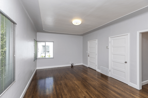 a living room with white walls and a white door and a window