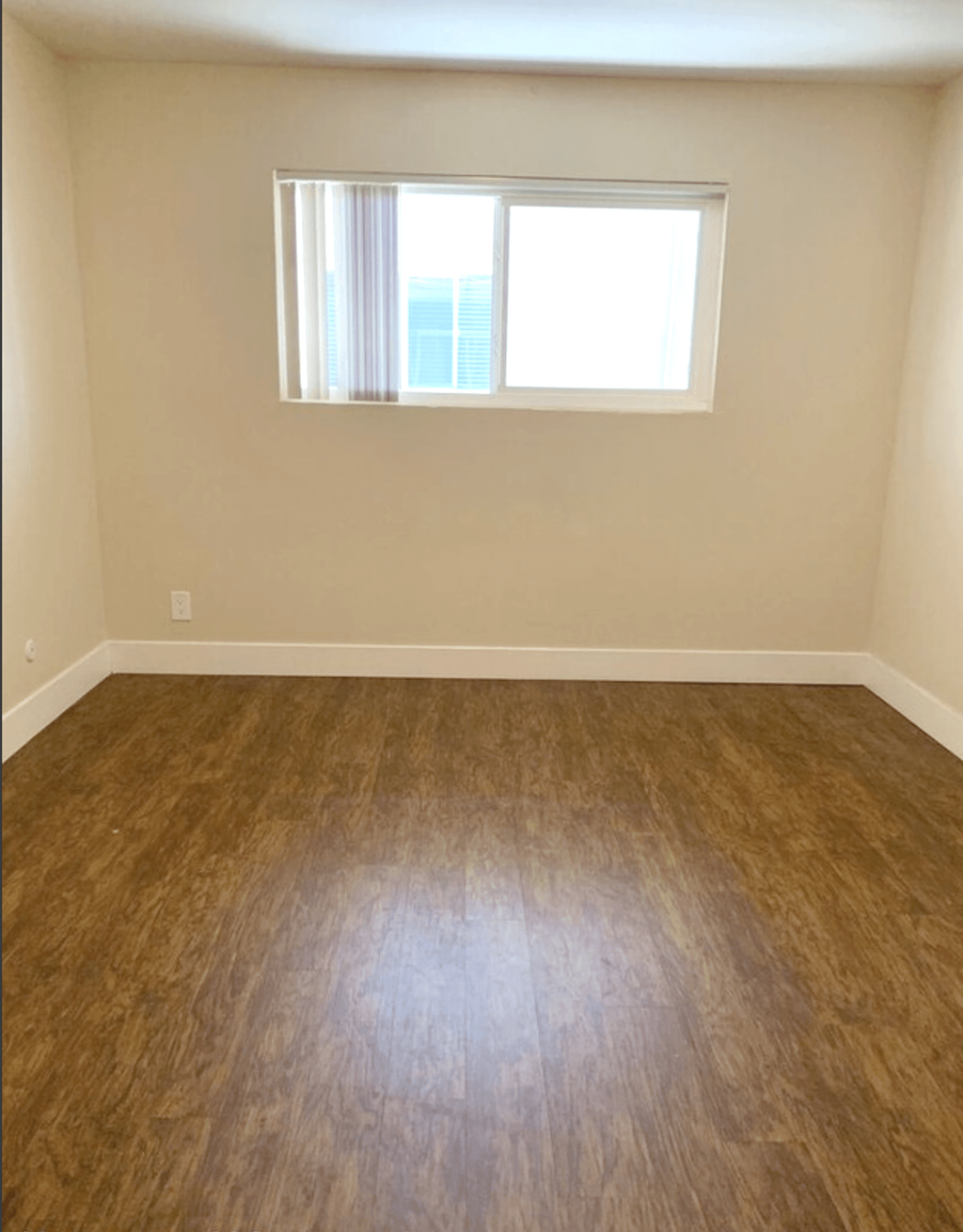 A room with a window and wooden flooring.