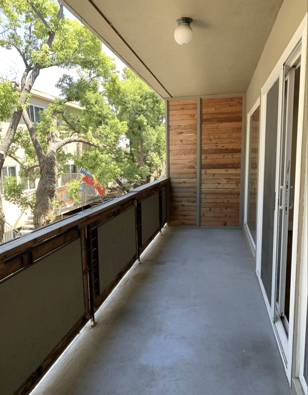 A balcony with a wooden wall and sliding glass doors.