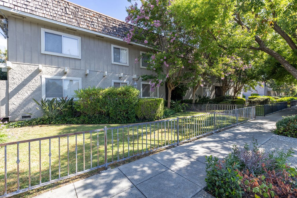 a white house with a yard behind a metal fence