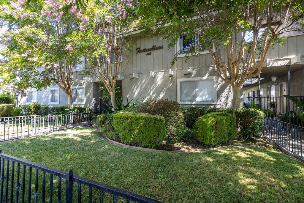 the exterior of an apartment building with a lawn and trees