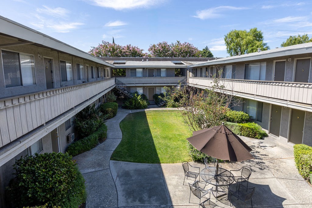 a courtyard with tables and chairs and an umbrella