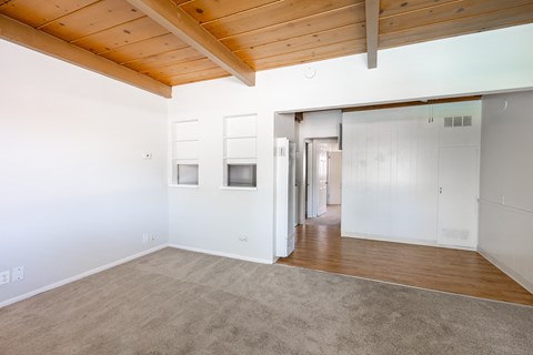 an empty living room with a wood ceiling and white walls