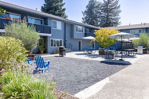 a patio with chairs and tables in front of a building