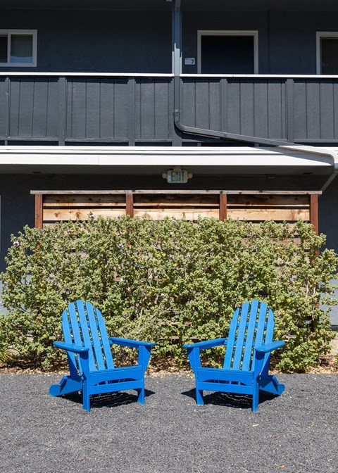 two blue chairs sitting in front of a building