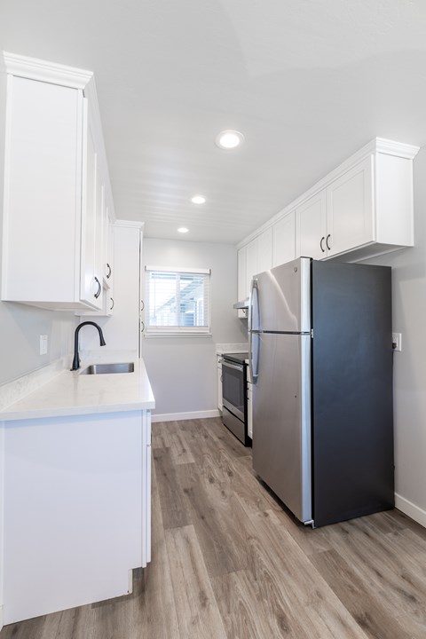 A kitchen with a stainless steel refrigerator and white cabinets.