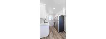 a renovated kitchen with white cabinets and a stainless steel refrigerator