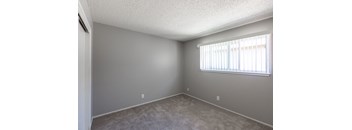 an empty living room with a window and carpet